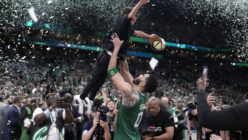 Boston Celtics forward Jayson Tatum (0) lifts his son Deuce as he celebrates with the team after the Celtics won the NBA championship with a Game 5 victory over Dallas Mavericks, Monday, June 17, 2024, in Boston. (AP Photo/Charles Krupa)