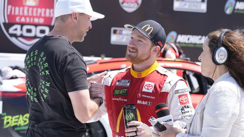 Tyler Reddick is greeted by Denny Hamlin after winning a NASCAR Cup Series auto race at Michigan International Speedway, Monday, Aug. 19, 2024, in Brooklyn, Mich. (AP Photo/Carlos Osorio)