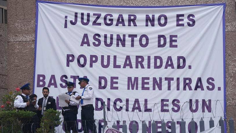 Security personnel stand at a federal court as unionized federal court workers gather outside to strike over reforms that would make all judges stand for election in Mexico City, Monday, Aug. 19, 2024. The sign reads in Spanish "Judging is not a popularity issue. Stop the lies. The judiciary is an honest power." (AP Photo/Fernando Llano)