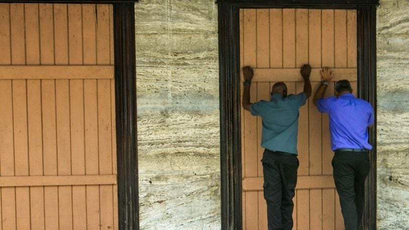 Residents board up a storefront pharmacy as they prepare for the arrival of Tropical Storm Dorian, in Bridgetown, Barbados, Monday, Aug. 26, 2019.