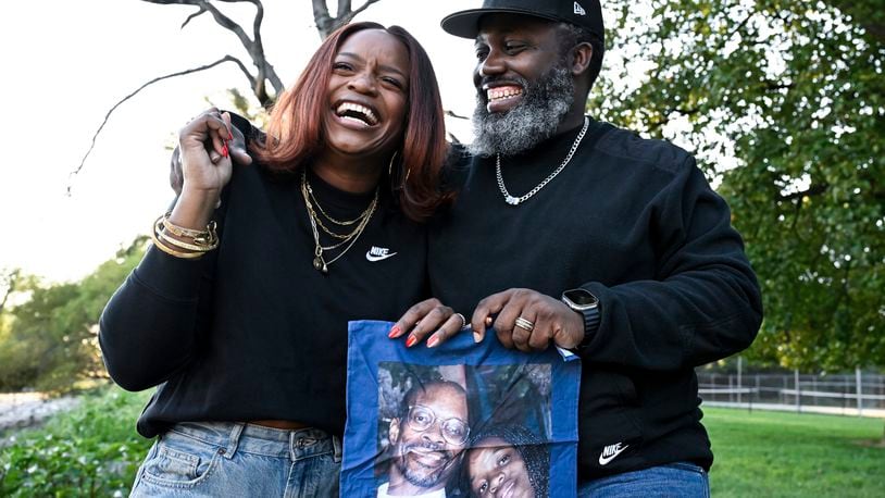 Ferguson activist Brittany Packnett-Cunningham, left, and her husband Reggie Cunningham, pose for an image while holding a handkerchief with picture of her father Rev. Ronald Packnett and Brittany, Saturday, Sep. 7, 2024, in Mount Rainier, Md. (AP Photo/Terrance Williams)