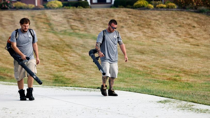 Dunham's Lawn Care employees Hayden Pond and Joshua Jackson blow grass off the driveway of a Greene County customer Wednesday, Sept. 25, 2024. The drought that has swept through Ohio and worsened over the past several weeks has turned area lawns brown and brittle. MARSHALL GORBY/STAFF