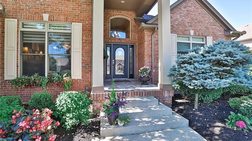 The brick and cedar home has a two story covered entry with a tile covered brick front porch.