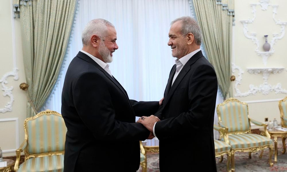 In this photo released by the Iranian Presidency Office, President Masoud Pezeshkian, right, shakes hands with Hamas chief Ismail Haniyeh at the start of their meeting at the President's office in Tehran, Iran, Tuesday, July 30, 2024. (Iranian Presidency Office via AP)