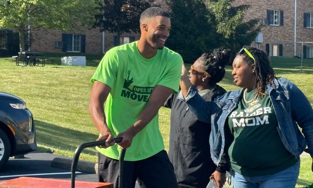 Volunteers helped unload cars and move students into residence halls as Debra Radford, left and Franchesca Alford, right, cheered for them on Wednesday morning. Eileen McClory/ staff