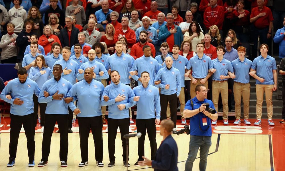 Dayton coaches and staff members stand for the national anthem before a game against St. Bonaventure on Friday, Feb. 2, 2024, at UD Arena. David Jablonski/Staff