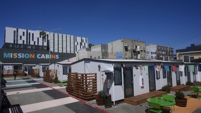 A person walks under a Mission Cabins sign at the Five Keys transitional housing location in San Francisco, Monday, Aug. 26, 2024. (AP Photo/Jeff Chiu)