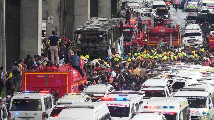 Rescuers gather at the site of a bus that caught fire, carrying young students with their teachers, in suburban Bangkok, Tuesday, Oct. 1, 2024. (AP Photo/Sakchai Lalit)