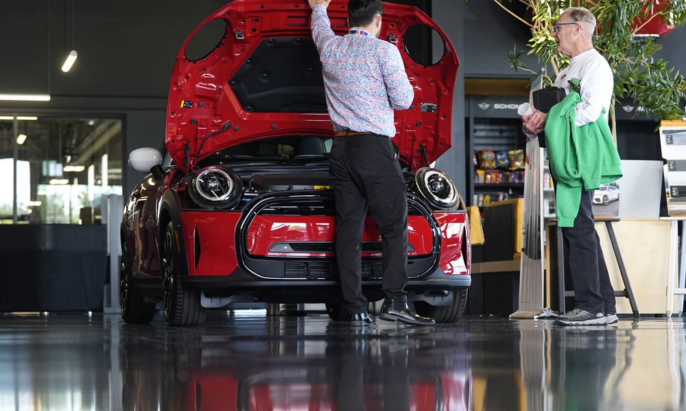 FILE - A salesperson shows an unsold 2024 Cooper SE electric hardtop to a prospective buyer in the showroom of a Mini dealership Wednesday, May 1, 2024, in Highlands Ranch, Colo. (AP Photo/David Zalubowski, File)