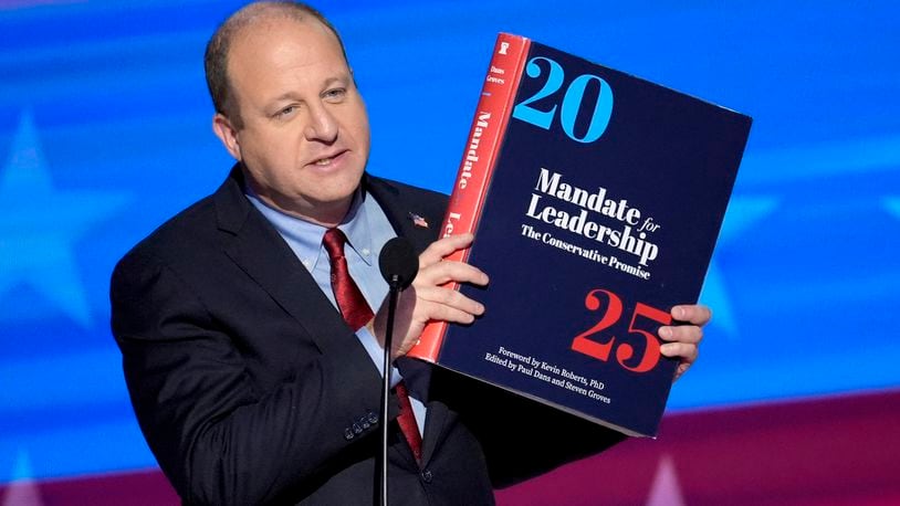 FILE - Colorado Gov. Jared Polis holds up a copy of Project 2025 as he speaks during the Democratic National Convention Aug. 21, 2024, in Chicago. (AP Photo/J. Scott Applewhite, File)