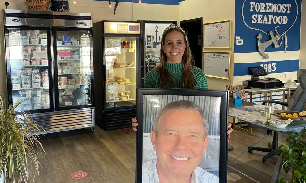 Kristen Patterson holds a photo of her dad, Tom Patterson, who is the founder of Foremost Seafood. He died on May 29, 2023. NATALIE JONES/STAFF