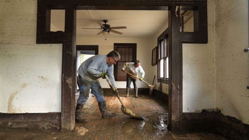 FILE - Ben Phillips, left, and his wife Becca Phillips scrape mud out of the living room of their home left in the wake of Hurricane Helene, Oct. 1, 2024, in Marshall, N.C. (AP Photo/Jeff Roberson, File)