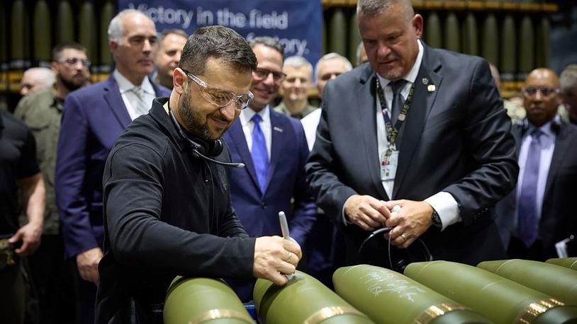 Ukrainian President Volodymyr Zelenskyy, left, is watched by Rich Hansen, the commander's representative for the Scranton Army Ammunition Plant, while signing military ordnance in Scranton, Pa., Sunday, Sept. 22, 2024. (Office of the Ukrainian Presidency via AP)