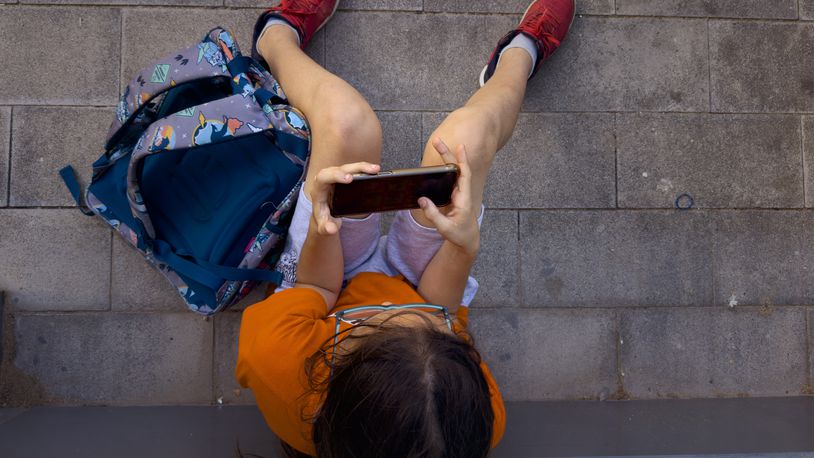 FILE - A 11-year-old boy plays with his father's phone outside school in Barcelona, Spain, Monday, June 17, 2024. (AP Photo/Emilio Morenatti, File)