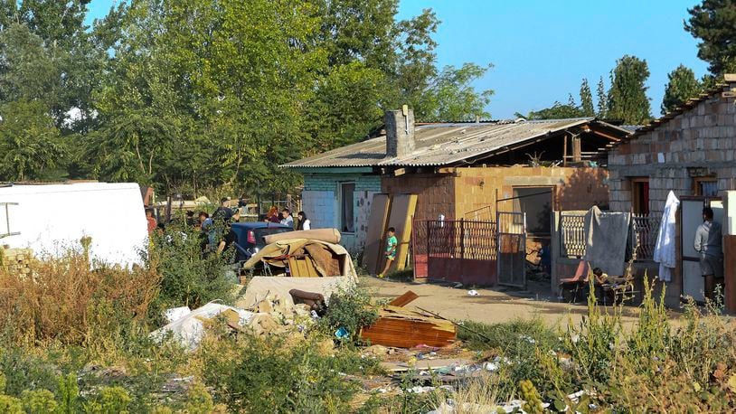 People stand in front of a small brick house after a fire in Novi Sad, some 90 kilometers (54 miles) north of Belgrade, Serbia, Friday, Aug. 23, 2024. (AP Photo)