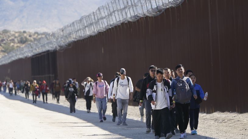 A group of people, including many from China, walk along the wall after crossing the border with Mexico to seek asylum, near Jacumba, Calif., Oct. 24, 2023. Ecuador on Tuesday, June 18, 2024, announced the suspension of an agreement with China that had waived visas for Chinese citizens traveling to the South American country, due to the increase in unusual migratory flows, using Ecuador as a starting point to reach other nations in the hemisphere through irregular routes, the Foreign Ministry said. (AP Photo/Gregory Bull, File)