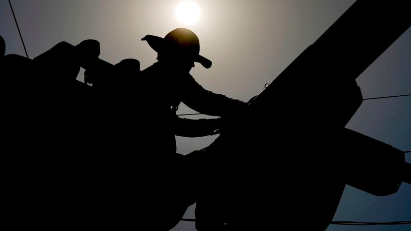 FILE - A linesman works on power lines under the morning sun, July 12, 2024, in Phoenix. (AP Photo/Matt York)