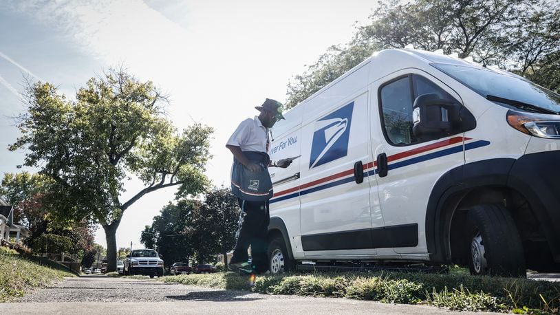 A mail carrier walks back to his truck after picking up and delivering mail on the eastside of Dayton. JIM NOELKER/STAFF