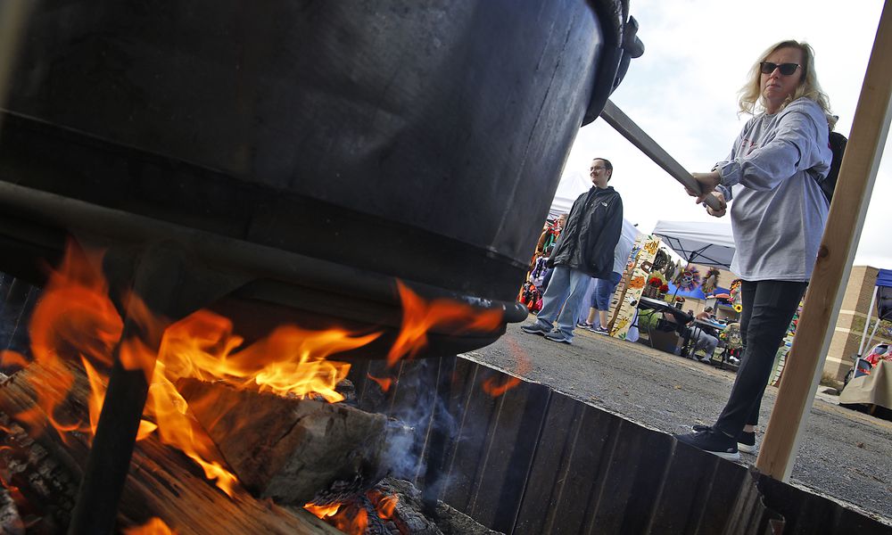 Cindy Leist takes a turn stirring one of the cauldrons of apple butter cooking over an open fire at the Enon Apple Butter Festival Saturday, Oct. 14, 2023. BILL LACKEY/STAFF