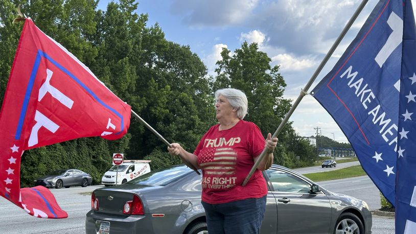 Suzanne Brown waves flags for Donald Trump before a ceremony to open his first Georgia campaign office, Thursday, June 13, 2024, in Fayetteville, Ga. Democratic President Joe Biden and former Republican President Donald Trump are working to win over Georgia voters ahead of the pair's first 2024 debate scheduled for Thursday, June 27, in Atlanta. (AP Photo/Jeff Amy)