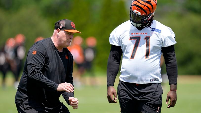 Cincinnati Bengals offensive line coach Frank Pollack, left, speaks with Amarius Mims (71) during a NFL football practice, Tuesday, May 28, 2024, in Cincinnati. (AP Photo/Jeff Dean)