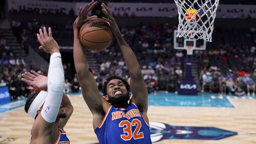 New York Knicks center Karl-Anthony Towns pulls down a rebound as guard Josh Hart looks on during the first half of a preseason NBA basketball game against the Charlotte Hornets, Sunday, Oct. 6, 2024, in Charlotte, N.C. (AP Photo/Chris Carlson)