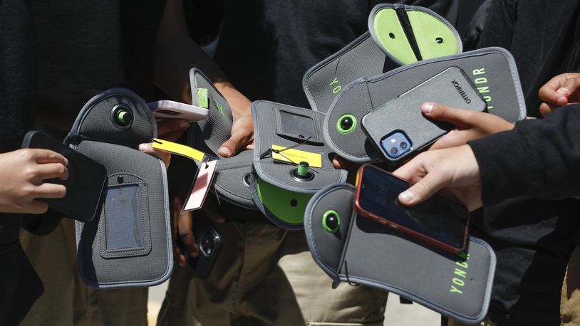 FILE - A student uses their cell phone after unlocking the pouch that secures it from use during the school day at Bayside Academy, Aug. 16, 2024, in San Mateo, Calif. (Lea Suzuki/San Francisco Chronicle via AP, File)