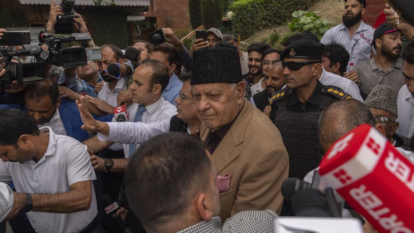 National Conference party leader Farooq Abdullah, center, wearing black cap, is surrounded by journalists as party celebrate early leads in the election for a local government in Indian controlled Kashmir, Srinagar, Tuesday, Oct. 8, 2024. (AP Photo/Dar Yasin)