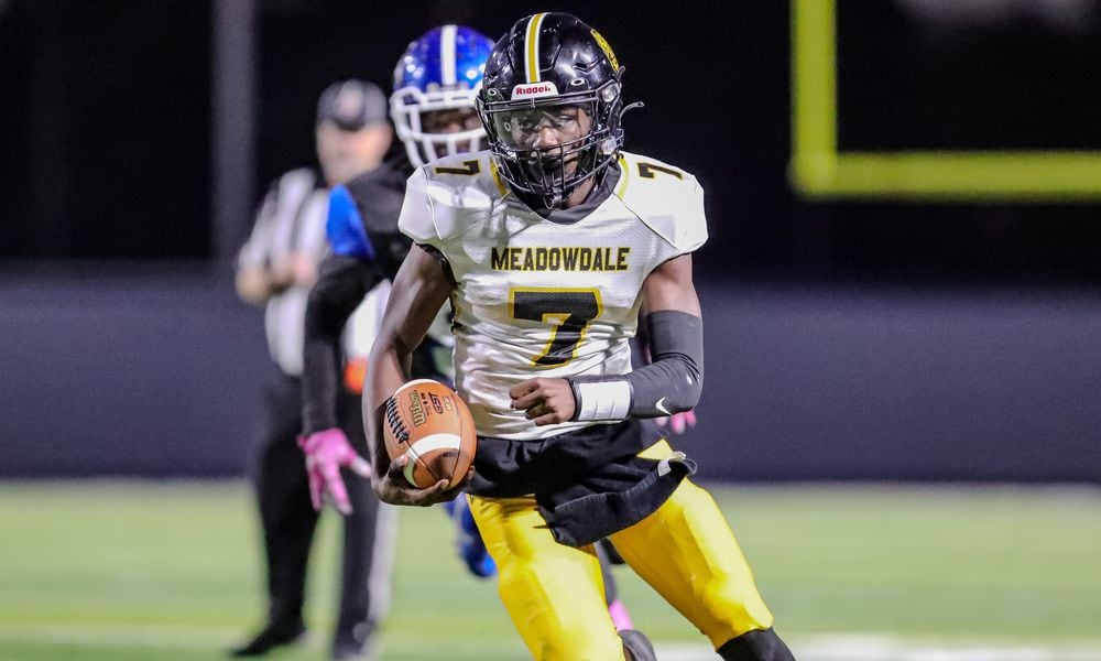 Meadowdale High School junior Jordan Brown runs past a Dunbar defender during their game on Thursday night at Dayton Welcome Stadium. The Lions won 44-14. CONTRIBUTED PHOTO BY MICHAEL COOPER