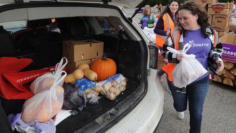 CareSource employees from left, Denise Johnson, Megan Post and Emily Smith place food into the back of a SUV Thursday, Oct. 19, 2023, at the mass food distribution at Wright State University’s Nutter Center. MARSHALL GORBY\STAFF