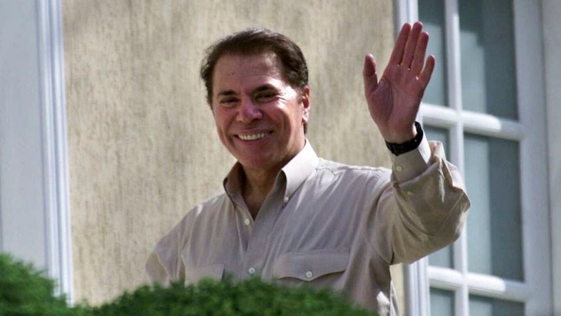 FILE - Brazilian TV mogul Silvio Santos waves from outside his home in Sao Paulo, Brazil on Thursday Aug. 30, 2001. (AP Photo/Dario Lopez-Mills)