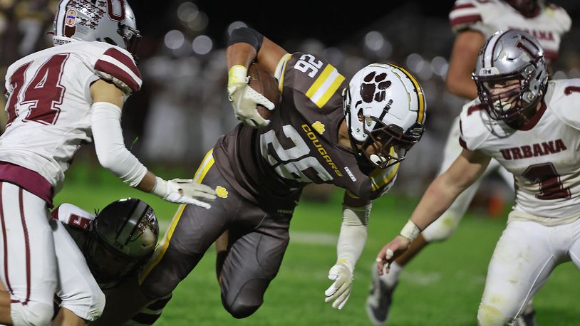 Kenton Ridge's Caleb Hall carries the ball between Urbana's Gio Torres, left, and Preston Wisma. BILL LACKEY/STAFF