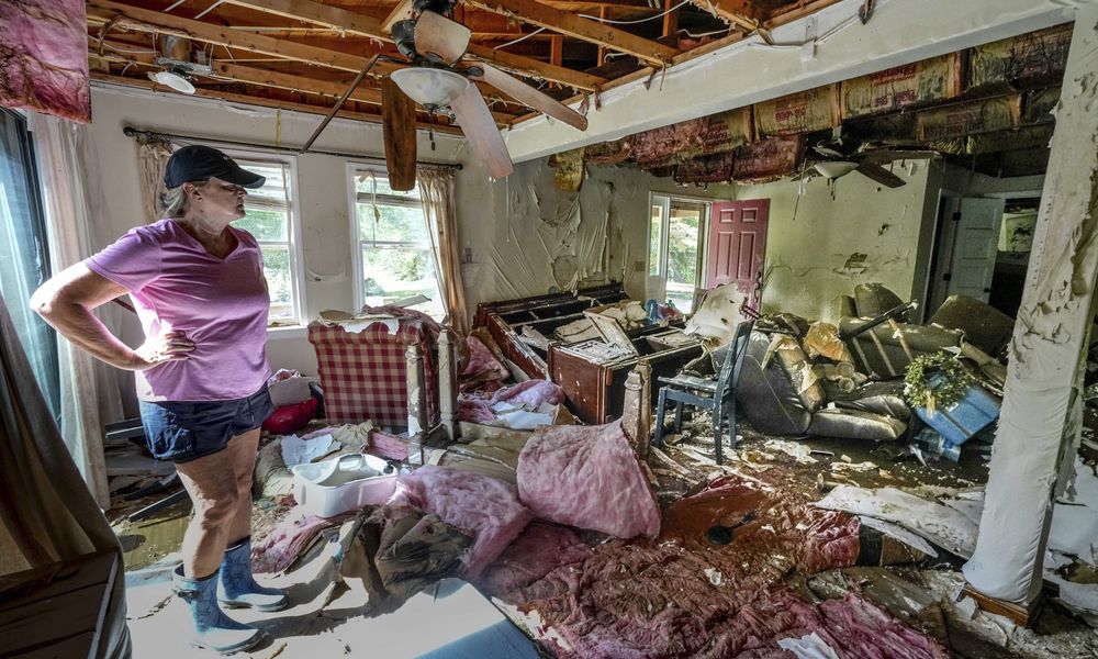 Cindy White looks over the devastation inside her home caused by Hurricane Helene, Tuesday, Oct. 1, 2024 in Morganton, N.C. The adjacent Catawba River flooded due to the torrential rains destroying the seven of family's nine homes on the property. (AP Photo/Kathy Kmonicek)