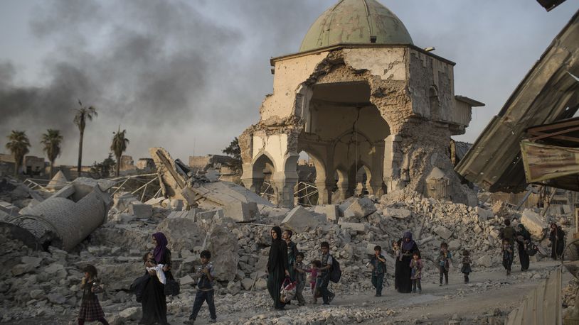 FILE - In this July 4, 2017, file photo, fleeing Iraqi civilians walk past the heavily damaged al-Nuri mosque as Iraqi forces continue their advance against Islamic State militants in Iraq's Old City of Mosul. The U.N. cultural agency has discovered five bombs hidden within the walls of the historic al-Nouri Mosque in the city of Mosul in northern Iraq, a remnant of the Islamic State militant group’s rule over the area, UNESCO said in a statement Saturday. The mosque, famous for its 12th-century leaning minaret, was destroyed by IS in 2017 and has been a focal point of UNESCO’s restoration efforts since 2020. (AP Photo/Felipe Dana, File)