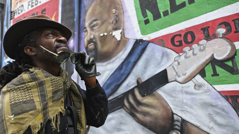 Mural artist Eric B. Ricks poses for a portrait in front of a mural that he oversaw and instructed young artist to paint in 2017 , Monday, Sept. 16, 2024, in Washington. (AP Photo/John McDonnell)