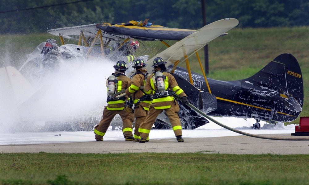 Firefighters work on the scene of a two-plane collision on the runway at Moraine Air Park in 2002. White fire retardant foam was sprayed on the planes and the surrounding area. Firefighting foams have been under scrutiny because many contain PFAS chemicals. JIM WITMER / STAFF