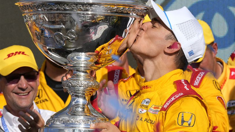 Alex Palou, right, kisses the trophy after winning his third IndyCar championship in four years Sunday, Sept. 15, 2024, at Nashville Superspeedway in Lebanon, Tenn. (AP Photo/Mark Humphrey)