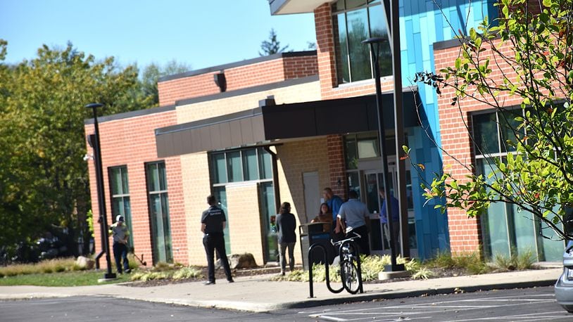 Security staff and other library employees stand outside the Dayton Metro Library Southeast Branch at 21 Watervliet Ave. after it closed down at 2:30 p.m. on a recent weekday. The library has reduced hours after a large fight broke out involving Belmont High School students. The school is next door to the library. CORNELIUS FROLIK / STAFF