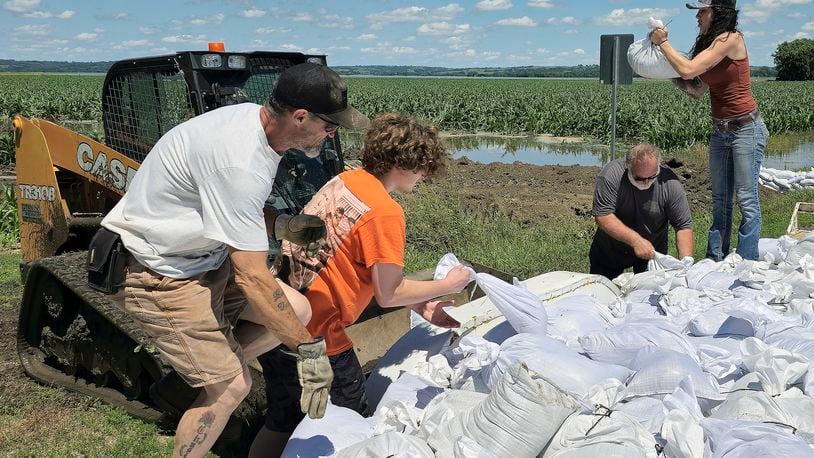 Volunteers toss sandbags into the bucket of a loader that will take them to be used to reinforce a berm on the northeast side of Jefferson, South Dakota, Sunday, June 23, 2024. The sandbag effort is an attempt to keep floodwaters from the Big Sioux River from inundating the town. (Tim Hynds/Sioux City Journal via AP)