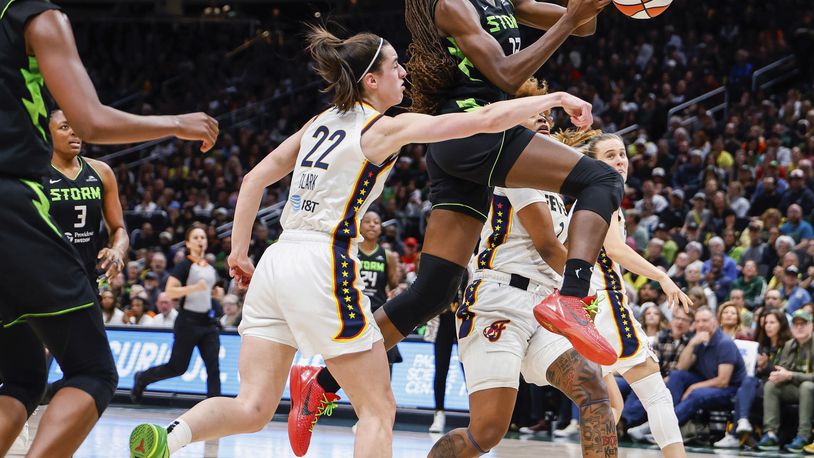 Indiana Fever's Caitlin Clark (22) punches the ball out of the hands of Seattle Storm's Ezi Magbegor during the first half of a WNBA basketball game Thursday, June 27, 2024, in Seattle. (Dean Rutz/The Seattle Times via AP)