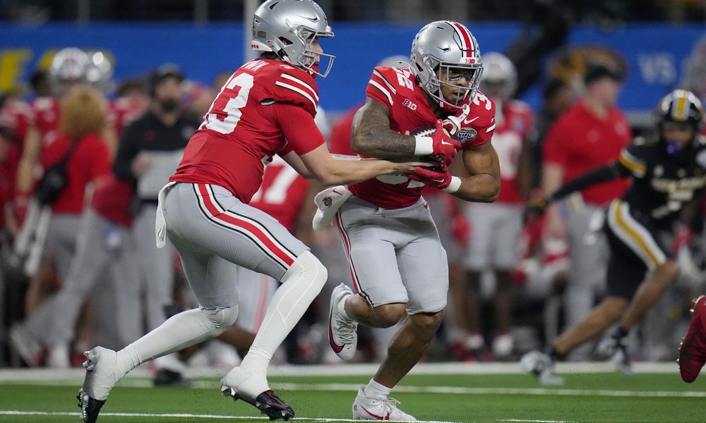 Ohio State quarterback Devin Brown, left, hands off to running back TreVeyon Henderson during the first half of the team's Cotton Bowl NCAA college football game against Missouri on Friday, Dec. 29, 2023, in Arlington, Texas. (AP Photo/Julio Cortez)