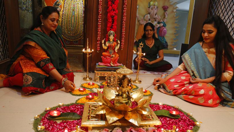 Indian Hindu women light earthen lamps on a rangoli, a hand decorated pattern on the floor, as part of Diwali festivities in Ahmadabad, India, Sunday, Nov. 4, 2018. Hindu festival of lights Diwali will be celebrated on Nov. 7.