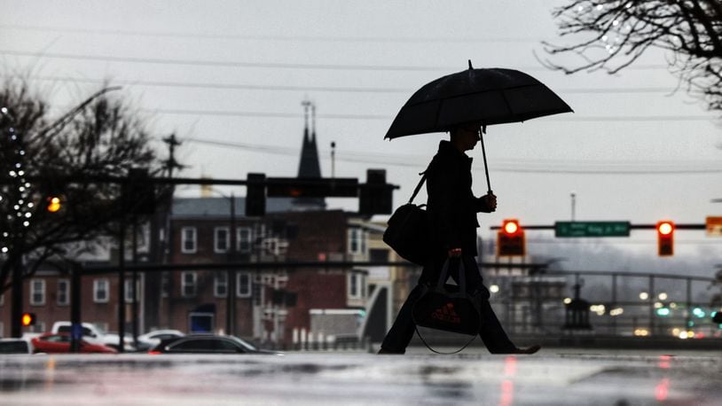 A man holds an umbrella as he crosses High Street in the rain Wednesday morning, Jan. 24, 2024, in Hamilton. NICK GRAHAM/STAFF