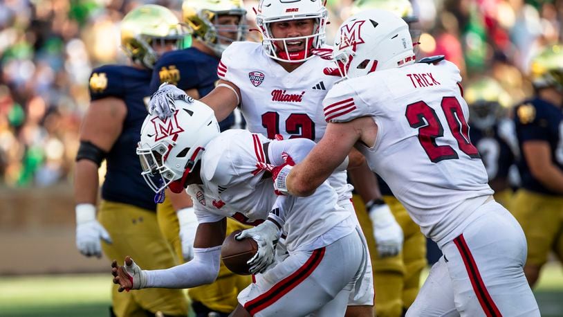 Miami (Ohio) linebackers Corban Hondru, center, and Adam Trick, right, celebrate with defensive back Luke Evans, left, after Evans recovered a fumble during the second half of an NCAA college football game against Notre Dame, Saturday, Sept. 21, 2024, in South Bend, Ind. (AP Photo/Michael Caterina)