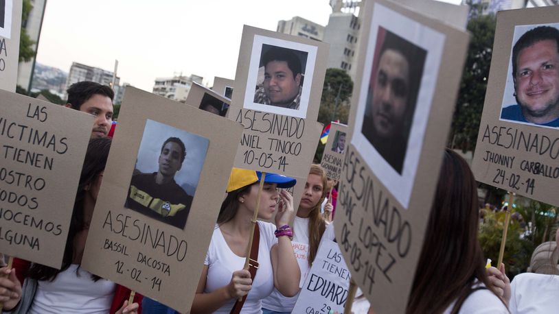 FILE - Demonstrators holds cardboard posters showing images of family and friends killed during anti-government protests, in Caracas, Venezuela, March 18, 2014. An Argentine federal court in Buenos Aires on June 28, 2024, concluded testimony from Venezuelan victims as part of an investigation into human rights abuses committed by security forces during the 2014 clamp down on mass anti-government protests. (AP Photo/Esteban Felix, File)