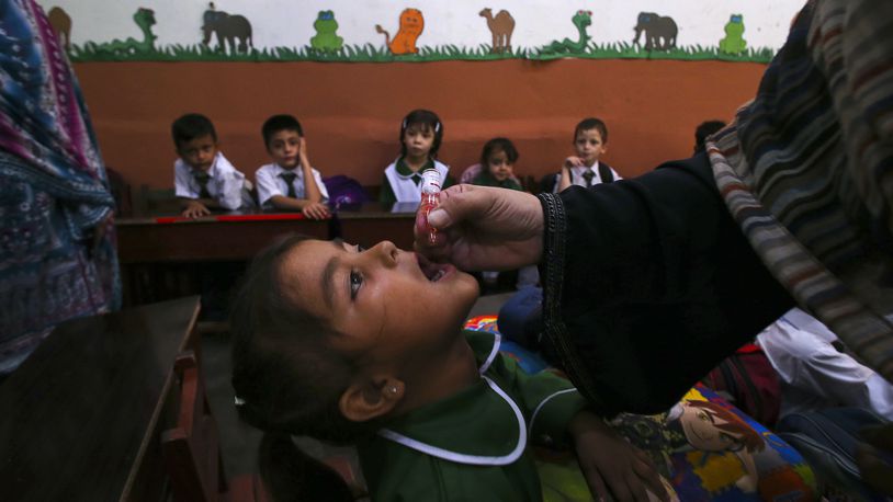 A health worker administers a polio vaccine to a child at a school in Peshawar, Pakistan, Monday, Sept. 9, 2024. (AP Photo/Muhammad Sajjad)