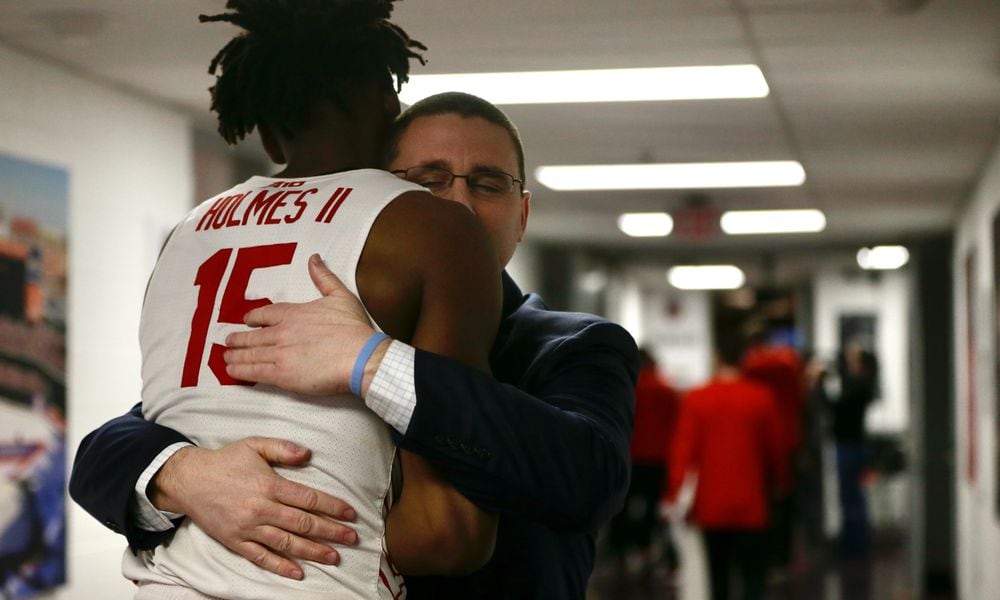 Dayton Athletic Director Neil Sullivan hugs DaRon Holmes II after a victory against Massachusetts on Friday, March 11, 2022, in the quarterfinals of the Atlantic 10 Conference tournament at Capital One Arena in Washington, D.C. David Jablonski/Staff