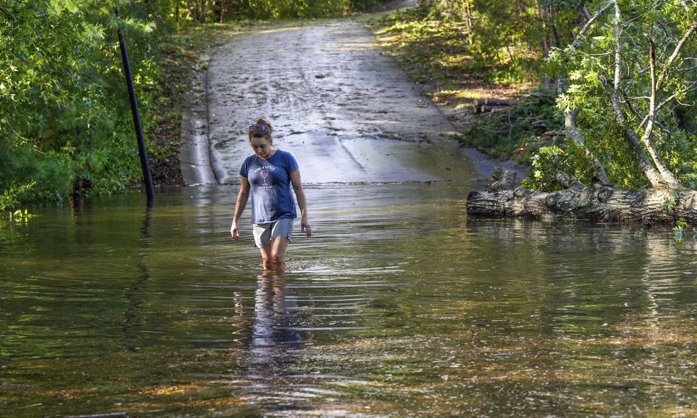 FILE - Teresa Elder walks through a flooded Sandy Cove Drive from Hurricane Helene, Sept. 27, 2024, in Morganton, N.C. (AP Photo/Kathy Kmonicek, File)