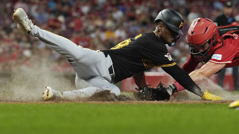 Pittsburgh Pirates' Michael A. Taylor dives safely past the tag by Cincinnati Reds catcher Tyler Stephenson to score in the sixth inning of a baseball game Tuesday, June 25, 2024, in Cincinnati. The Pirates won 9-5. (AP Photo/Carolyn Kaster)