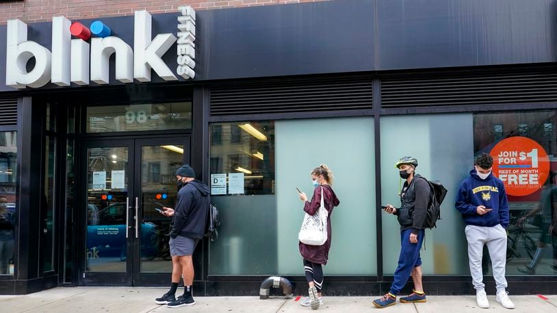 FILE — People line up outside the Blink Fitness gym, March 26, 2021, in the Lower East Side neighborhood of New York. (AP Photo/Mary Altaffer, File)